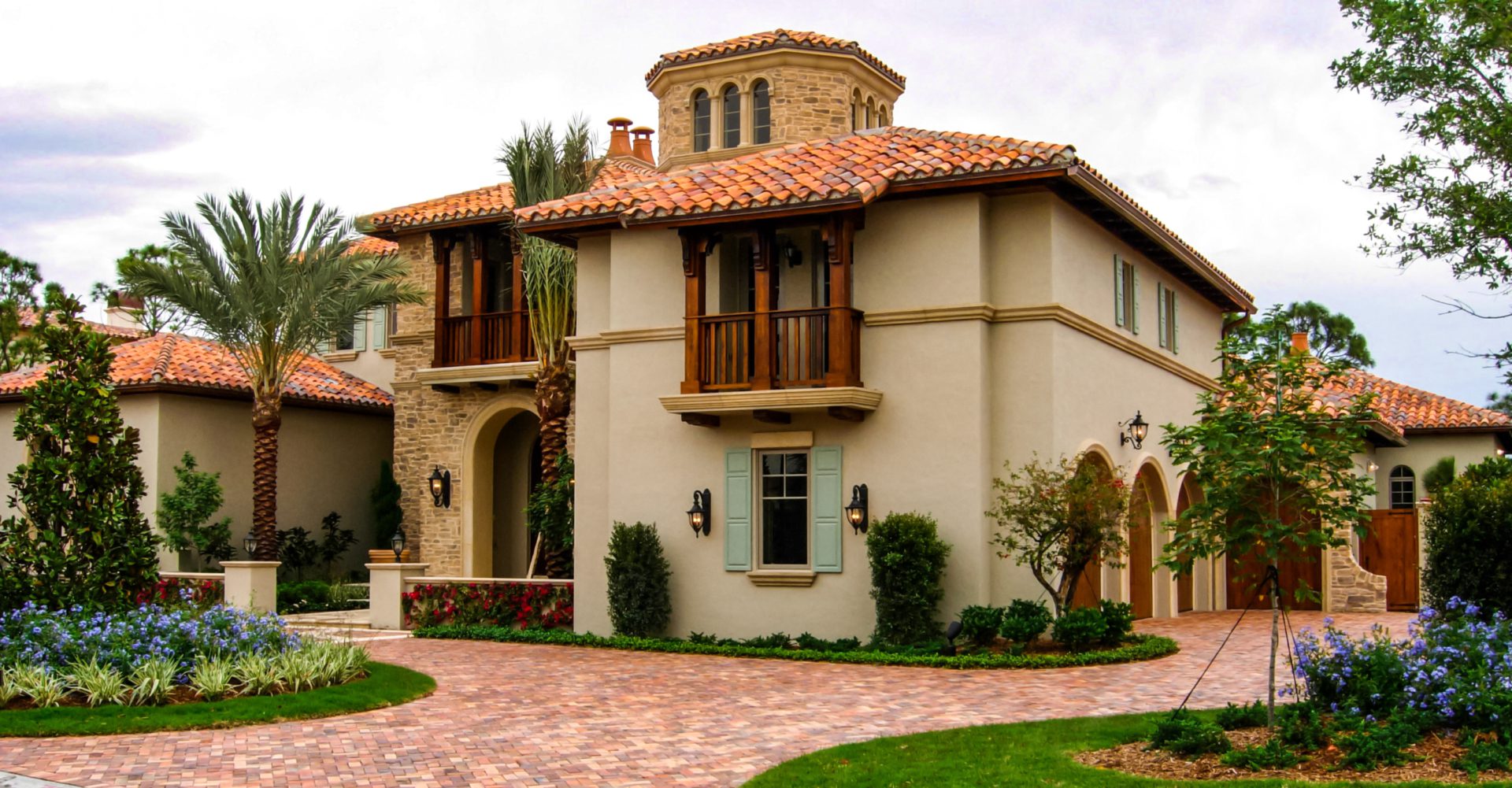 A beautiful mediterranean style home with a brick driveway.