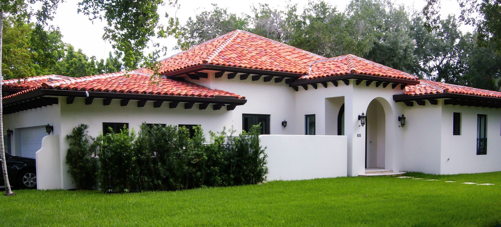 A house with a red tile roof and green grass.