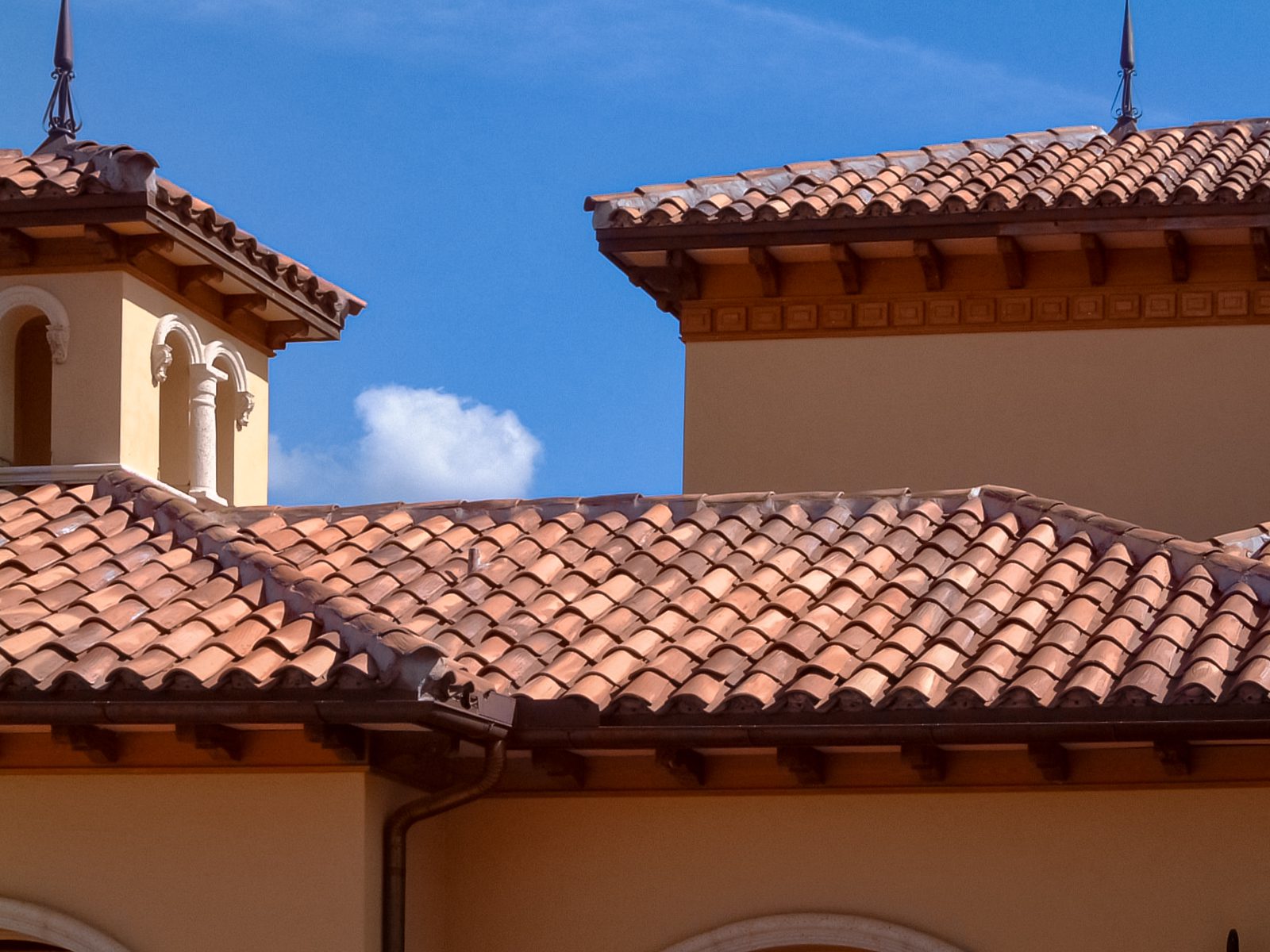 A roof with tan tile and a blue sky.